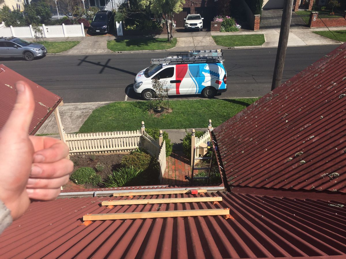 view from the roof of a home. In the foreground the photographer gives a thumbs up. On the street is the Butler Plumbing van.